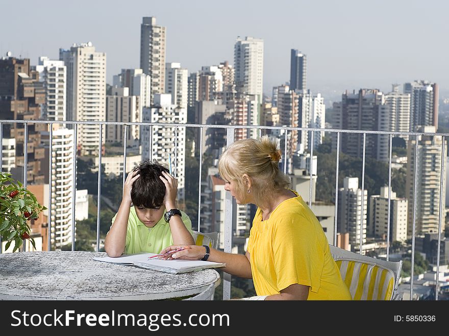 Woman instructing boy while sitting on balcony overlooking city. Horizontally framed photo. Woman instructing boy while sitting on balcony overlooking city. Horizontally framed photo.