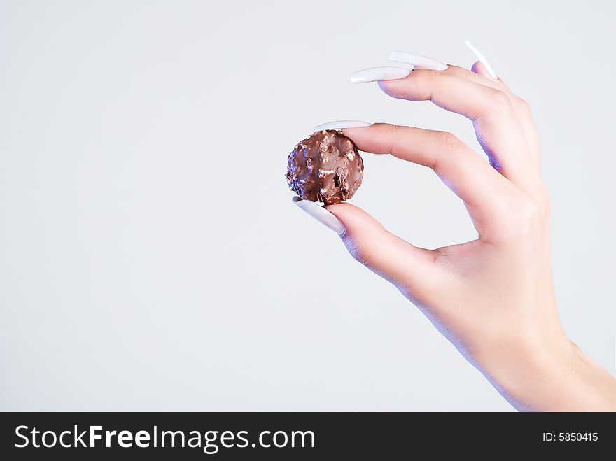 Womanish hand on a white background, holding a chocolate candy