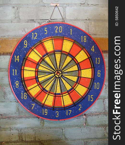 A colorful dartboard is displayed sideways on a brick wall.  Horizontally framed photo. A colorful dartboard is displayed sideways on a brick wall.  Horizontally framed photo.