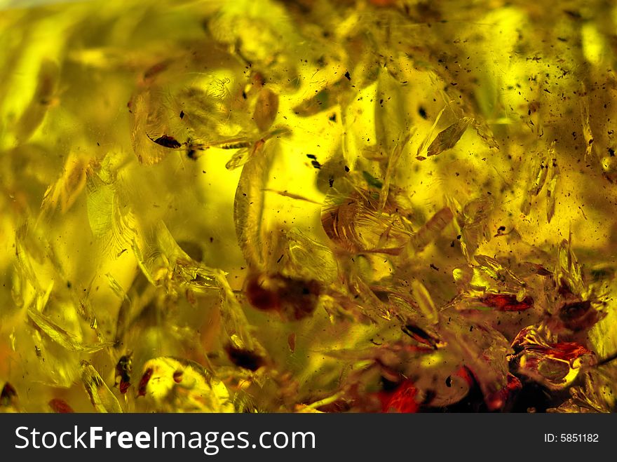 Extreme closeup of small piece of polished amber, natural particles inside. Extreme closeup of small piece of polished amber, natural particles inside