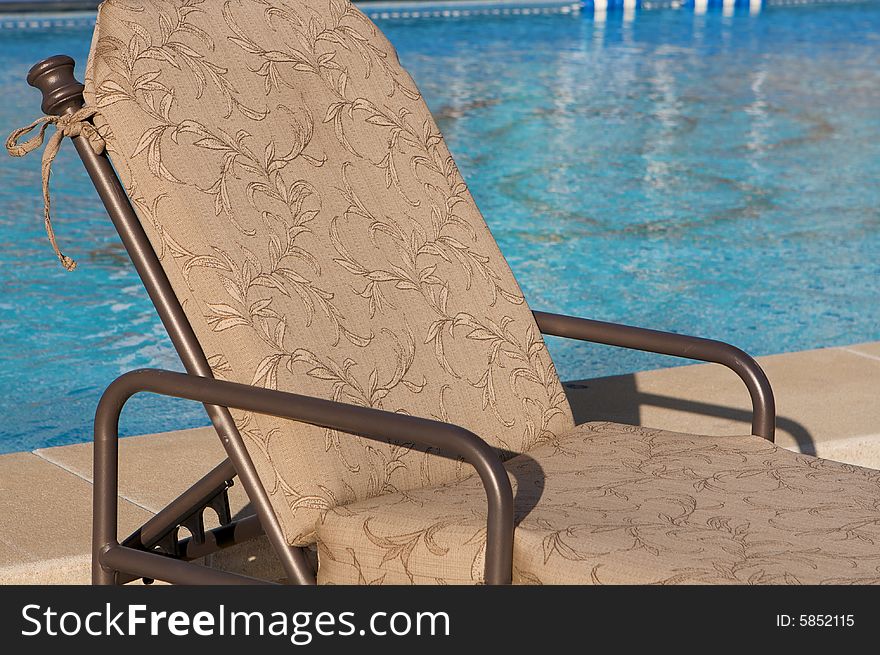 An image of a patio chair next to an aqua blue pool