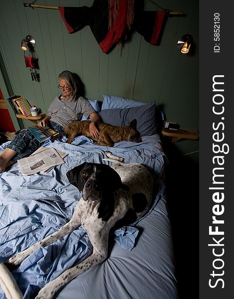 Senior woman in bed reading magazine, with dog. Senior woman in bed reading magazine, with dog