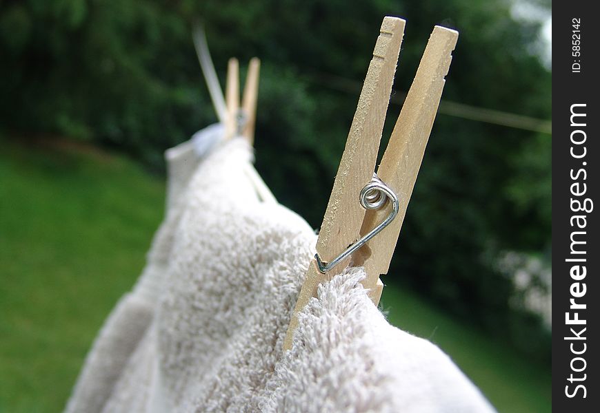 Wooden clothes pins holding towel on clothes line to dry. Wooden clothes pins holding towel on clothes line to dry