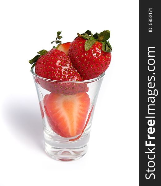Strawberries cut in a shot glass on white background