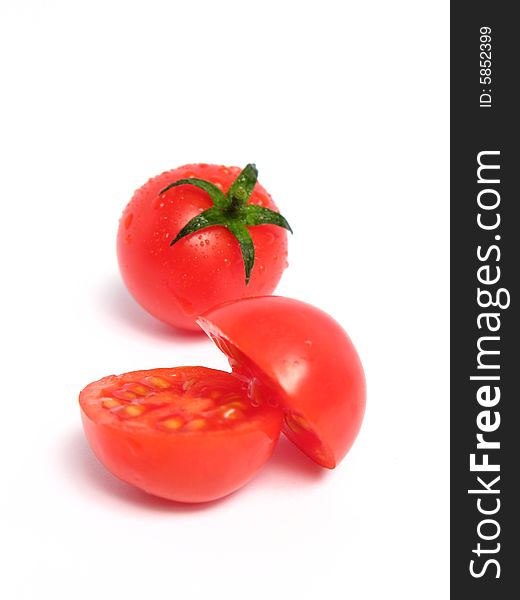 Two cherry tomatoes together and one is cut in the middle, on a white background
