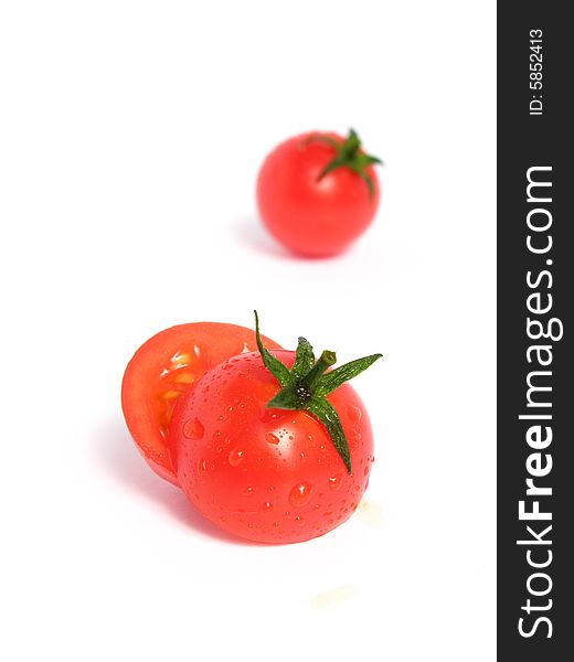 Two cherry tomatoes together and one is cut in the middle, on a white background