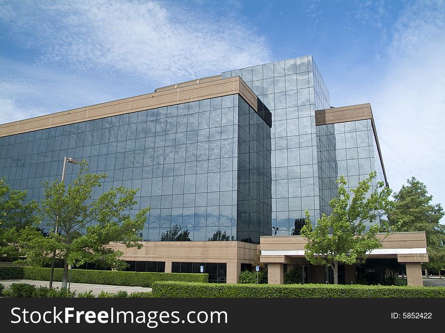 A building with a glass exterior reflecting the sky and clouds above. A building with a glass exterior reflecting the sky and clouds above.