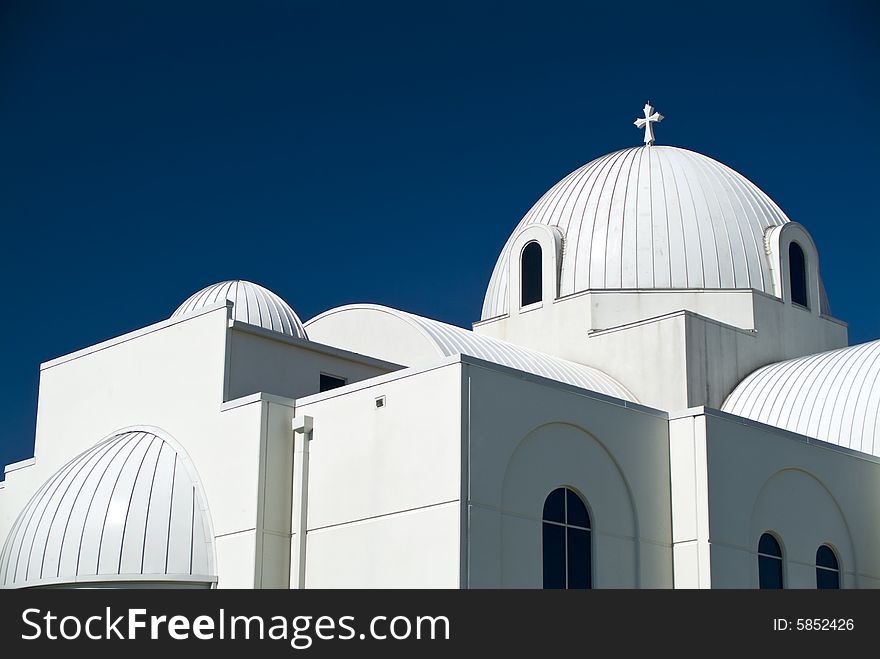 A domed Christian church whose stark white color contrasts sharply wih the dark blue sky. A domed Christian church whose stark white color contrasts sharply wih the dark blue sky.