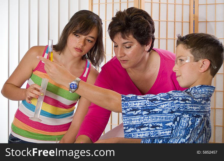 A woman who appears to be a teacher working with two children on a chemistry project. A woman who appears to be a teacher working with two children on a chemistry project.