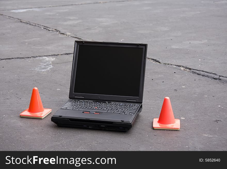Laptop with mini-traffic cones on blacktop. Laptop with mini-traffic cones on blacktop