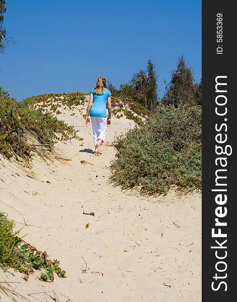 Young Teen Girl Walking up Sand Dune at Beach