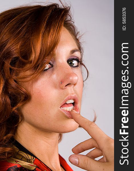 Redhead girl with finger on lips with white background