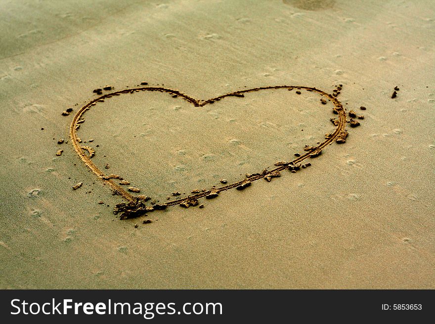 Drawe heart shape on sand