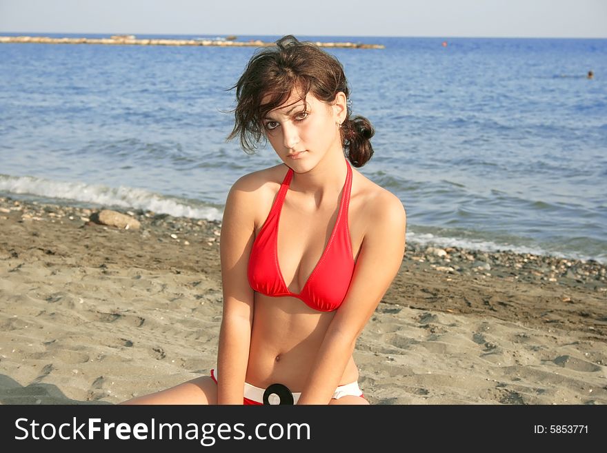 Pretty girl in red bikini on the sand.