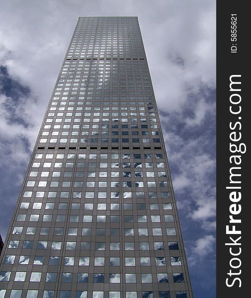 A tall glass skyscraper in downtown Denver almost blends into the sky as it reflects the surrounding clouds. A tall glass skyscraper in downtown Denver almost blends into the sky as it reflects the surrounding clouds.