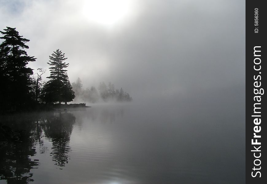 Foggy mist over lake in Adirondacks as the sun rises.