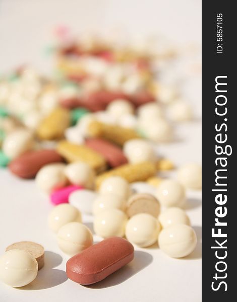 Various pills against white background with shallow depth of field on foreground. Various pills against white background with shallow depth of field on foreground