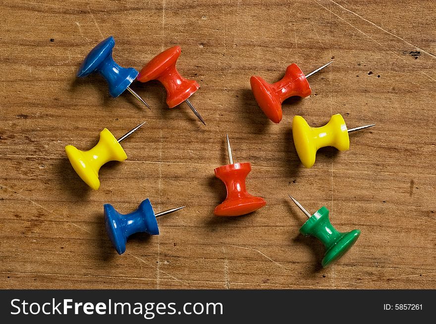 Assorted pushpins on different colors on wooden board.