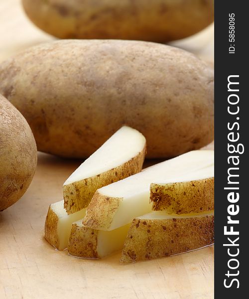 Fresh cut potatoes on a wooden cutting board.