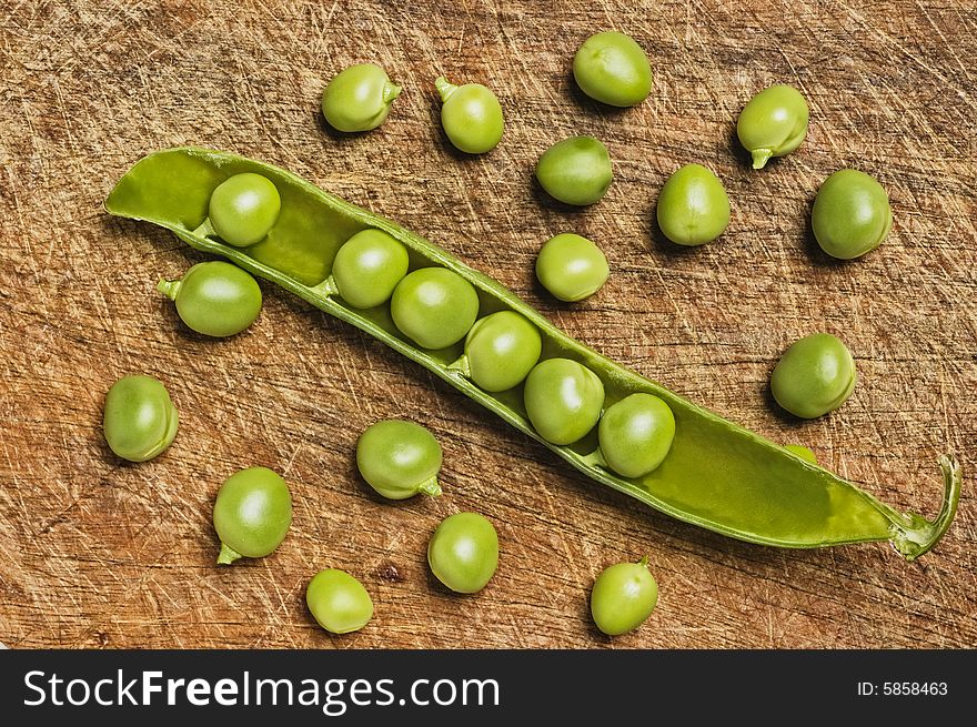 Fresh green peas on wooden background, studio shot. Fresh green peas on wooden background, studio shot.