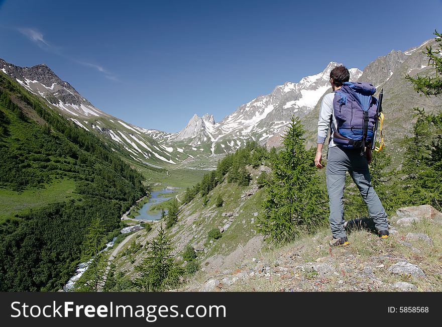 Male hiker enjoying the view over the beautiful landscape of Mige Lake, Mont Blanc, Courmayeur, Italy. Male hiker enjoying the view over the beautiful landscape of Mige Lake, Mont Blanc, Courmayeur, Italy