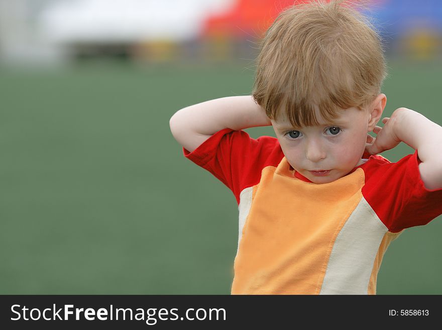 Portrait of the kid on a background of a green field of stadium