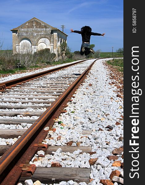 Young woman jumping on the railway of an abandoned train station. Young woman jumping on the railway of an abandoned train station.