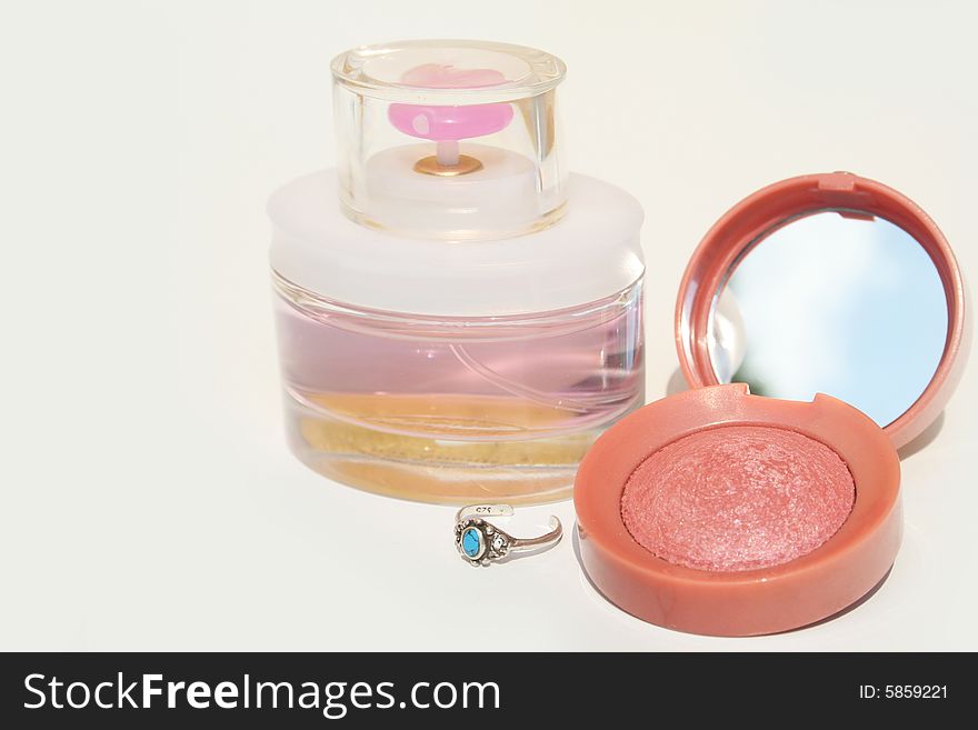 Perfume, blush and a blue stone ring on white background with copy space on left. Perfume, blush and a blue stone ring on white background with copy space on left