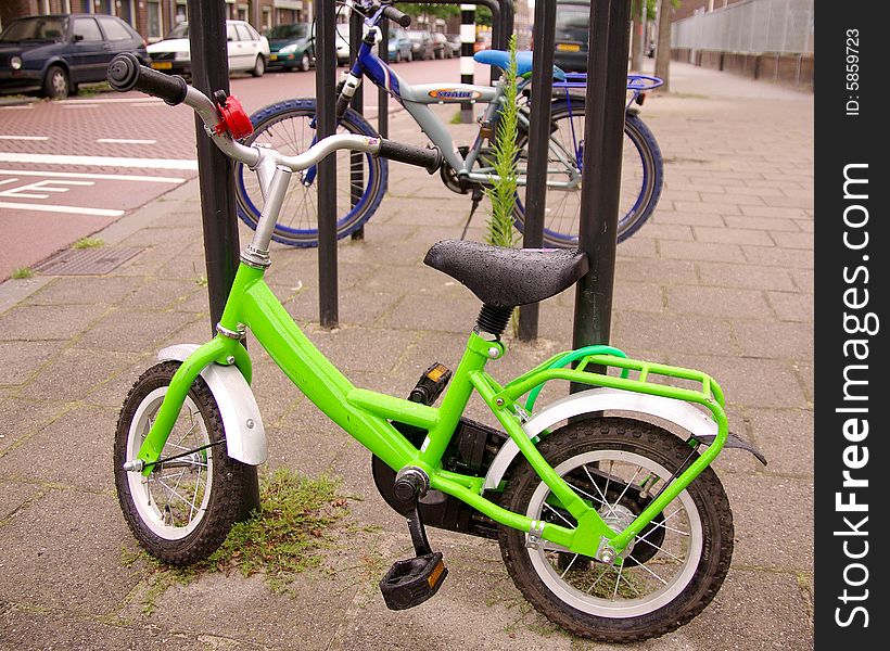 An apple green child's bicycle, parked in the street