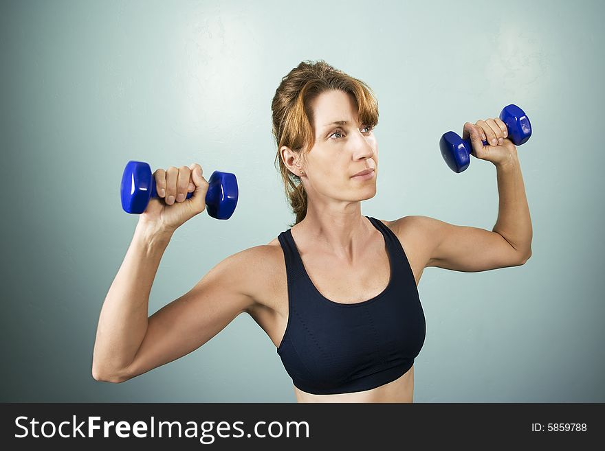 Pretty athletic woman working out with dumbbells. Pretty athletic woman working out with dumbbells