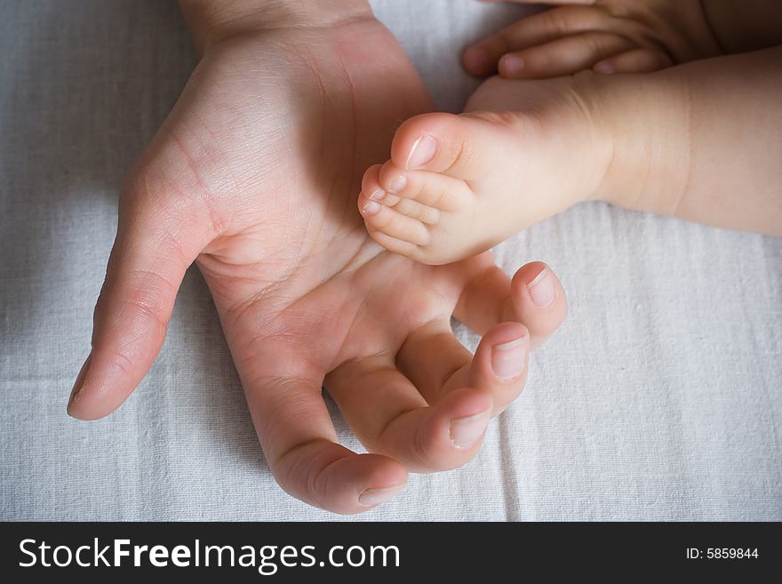 Mother is holding small baby arm and foot