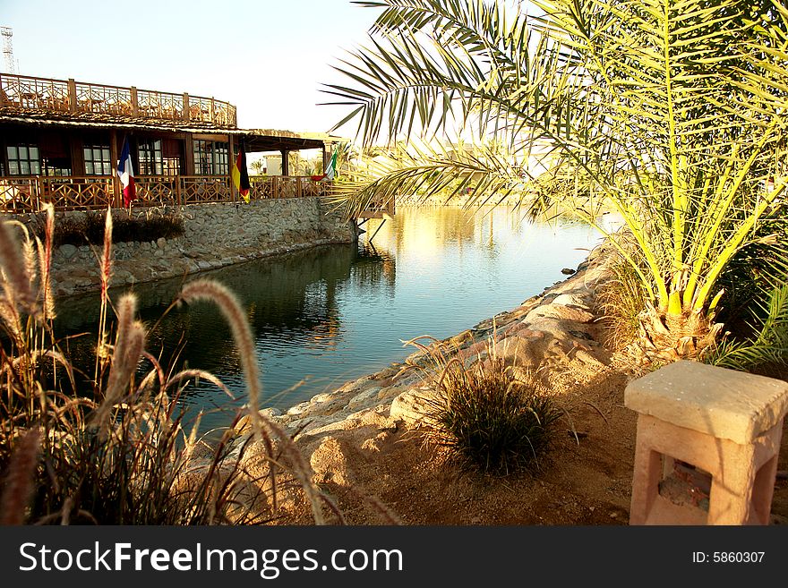 Cafe on seacoast. In the foreground a palm tree