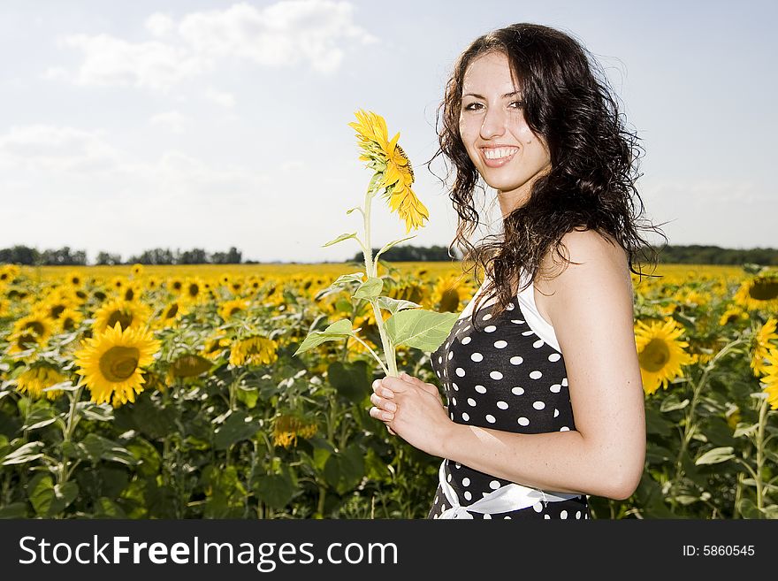 Smiling girl with sunflower on meadow