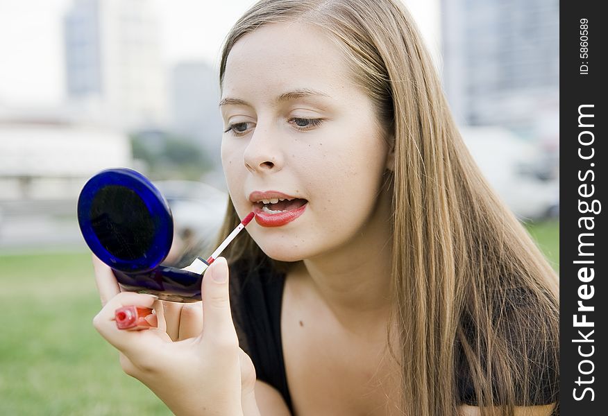 Girl doing makeup in city