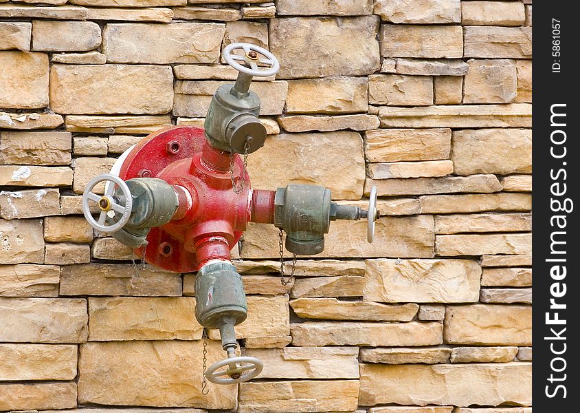 A red fire hydrant on a rock masonry wall. A red fire hydrant on a rock masonry wall