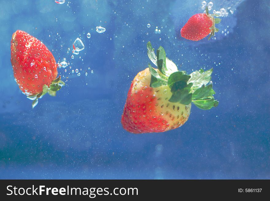 Strawberries falling in deep blue water. Strawberries falling in deep blue water