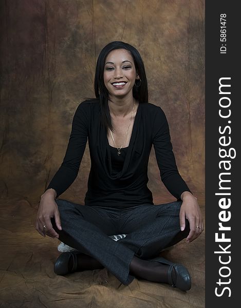 A young lady sitting cross legged smiling. A young lady sitting cross legged smiling.