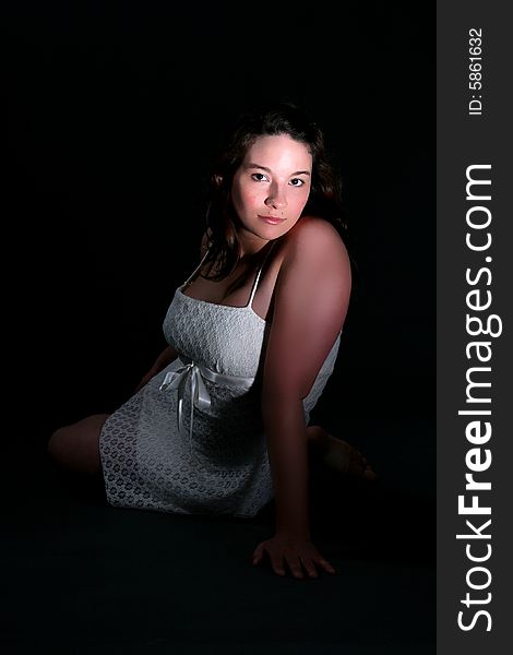 Young woman sitting with dramatic lighting. Young woman sitting with dramatic lighting