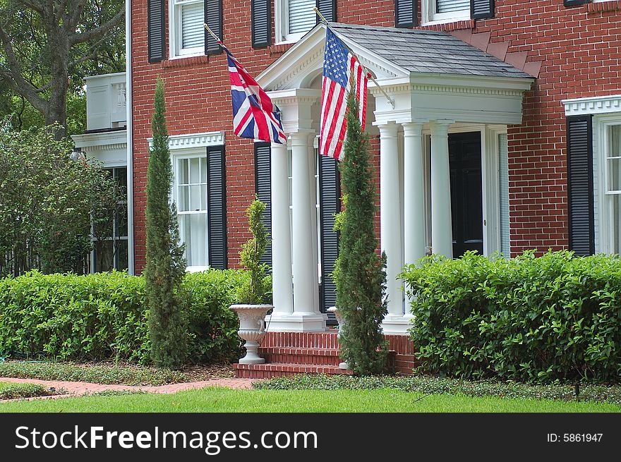 American flag and Union Jack flying in front of brick house. American flag and Union Jack flying in front of brick house.