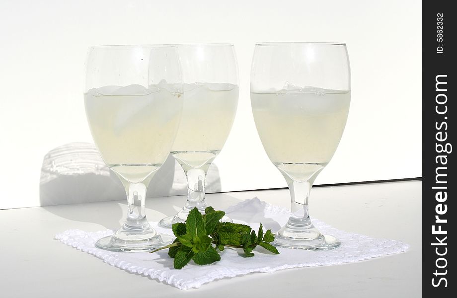Three glasses of lemonade and a sprig of mint.