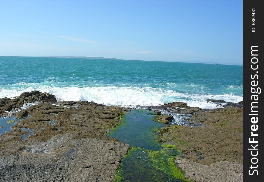 A stream runs through a meadow into the ocean. A stream runs through a meadow into the ocean.