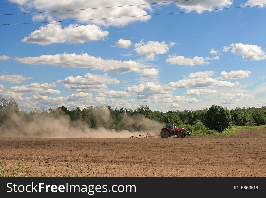 A tractor on a tillage in the daytime. A tractor on a tillage in the daytime