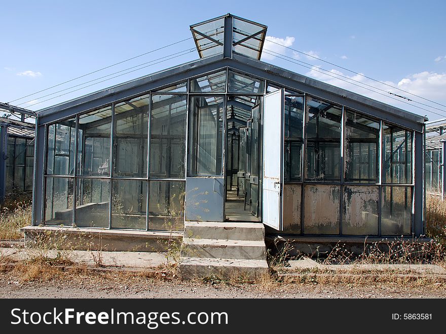 A greenhouse made entirely of glass sits on a green lawn under a blue sky. A greenhouse made entirely of glass sits on a green lawn under a blue sky.