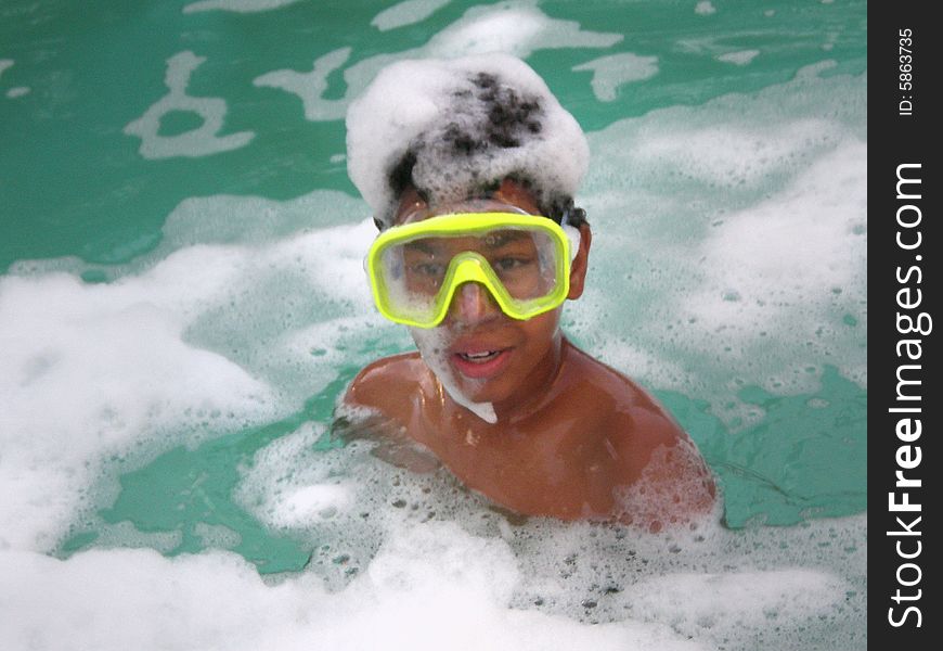 A picture of a black boy in a pool with a goggles or a swim mask with bubbles around him. A picture of a black boy in a pool with a goggles or a swim mask with bubbles around him.