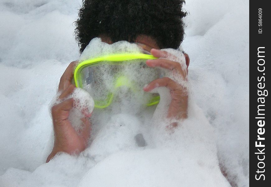 A picture of a black boy with a swim mask or goggles covered in lots of bubbles. A picture of a black boy with a swim mask or goggles covered in lots of bubbles.