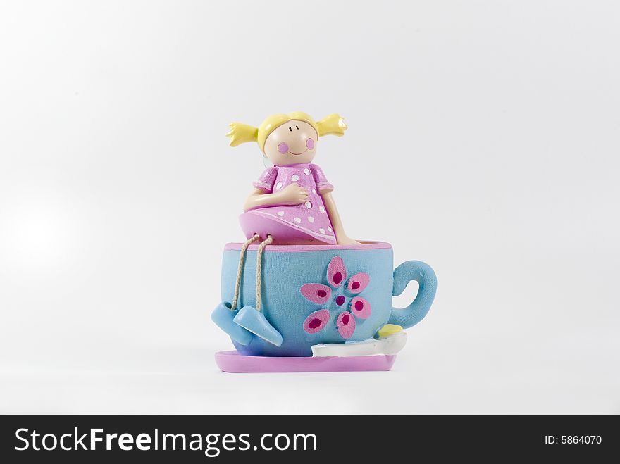 A coin box looks as a girl in pink sitting on a blue cup. A coin box looks as a girl in pink sitting on a blue cup