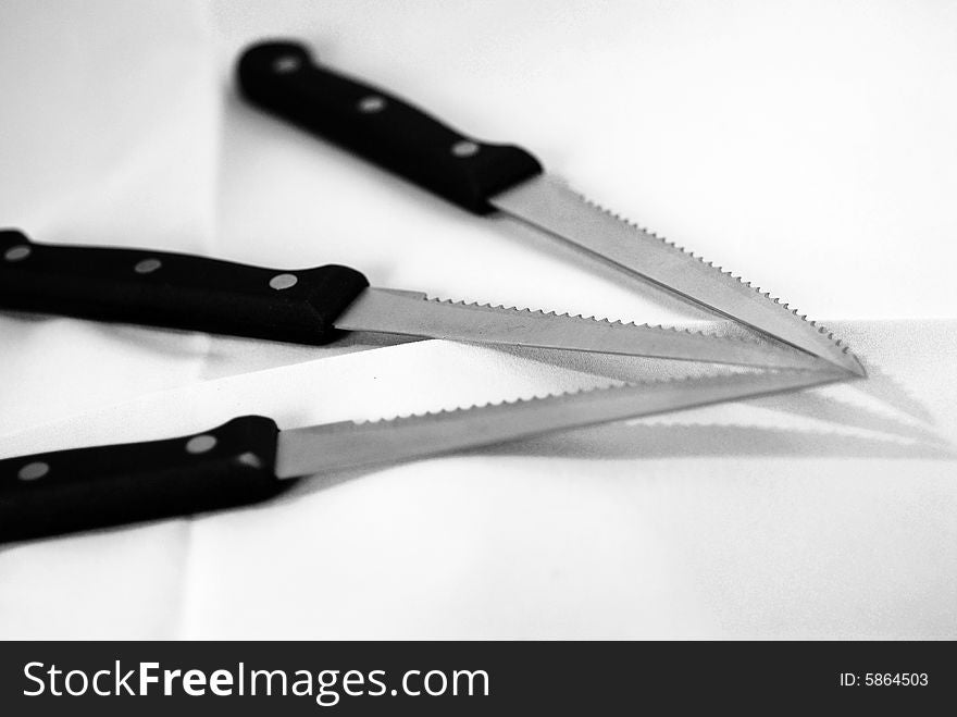 A black and white photograph of three knives arranged together. A black and white photograph of three knives arranged together