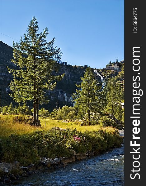 Alpine creek with waterfall in the distance