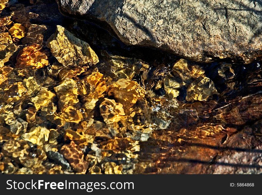 Pebbles in a mountain stream with flowing crystalline water. Pebbles in a mountain stream with flowing crystalline water