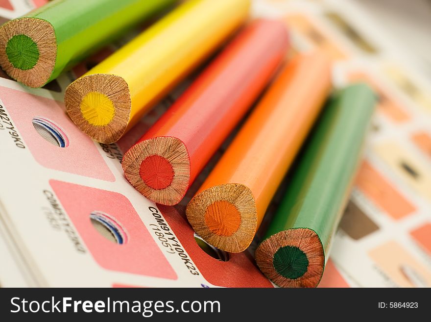 Orange, red, yellow, green pencils on cmyk color bars. Orange, red, yellow, green pencils on cmyk color bars